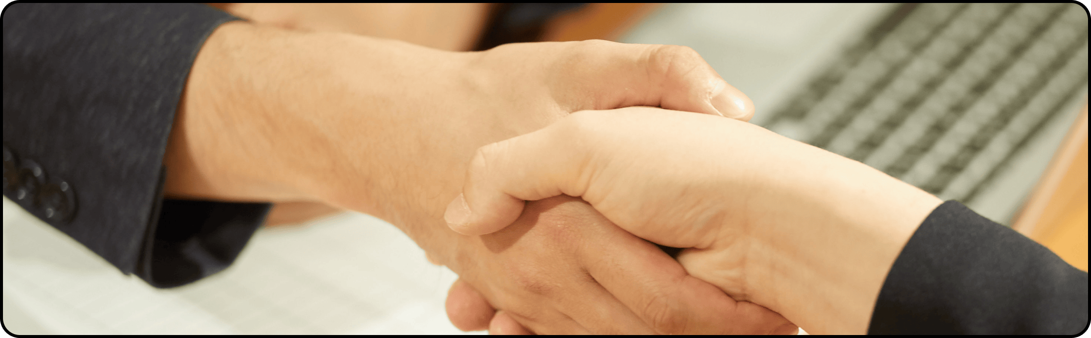 テーブル越しに握手を交わすシーン